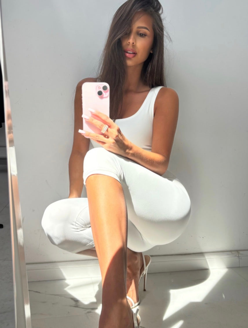 Liv white capri jumpsuit styled with white heels, seated view