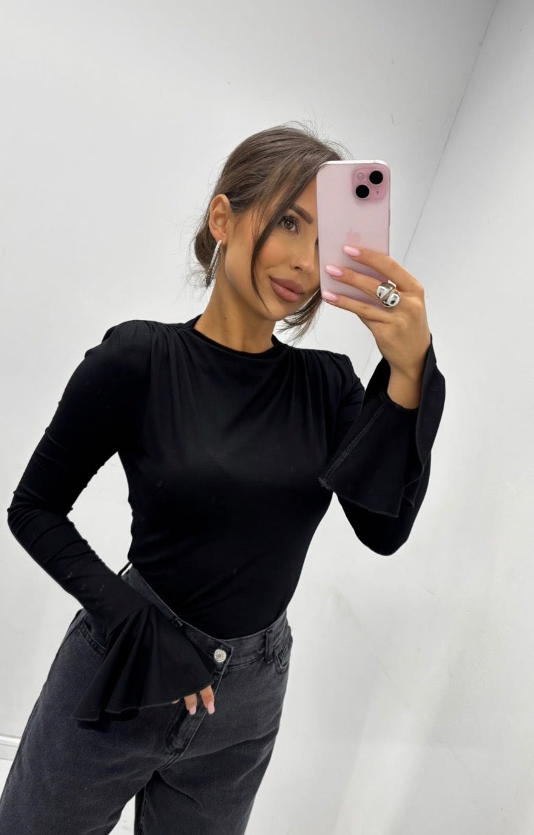 Close front view of Veronica black top with padded shoulders and flared cuffs